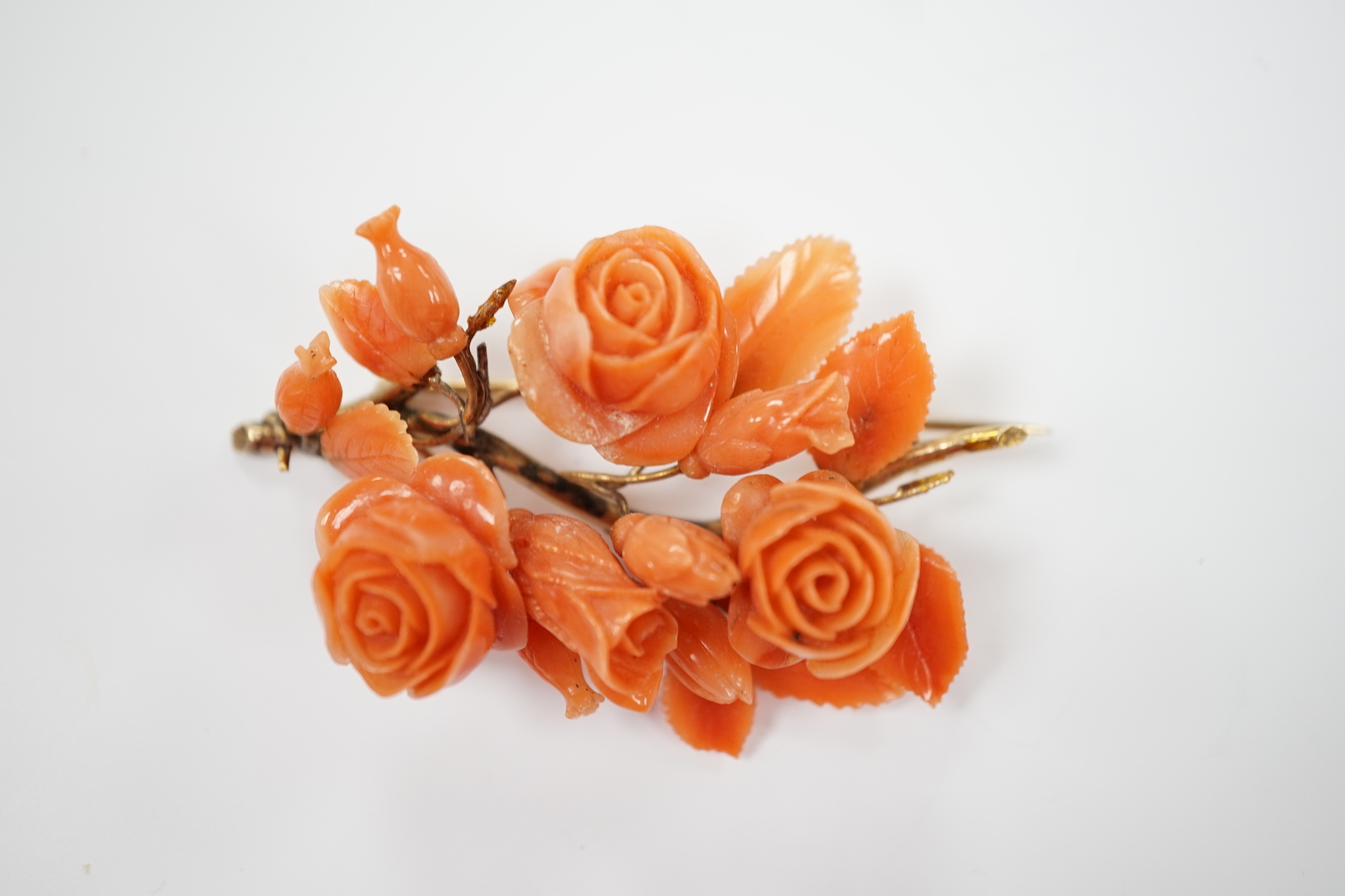 A yellow metal mounted carved coral floral spray brooch(a.f.), 64mm.